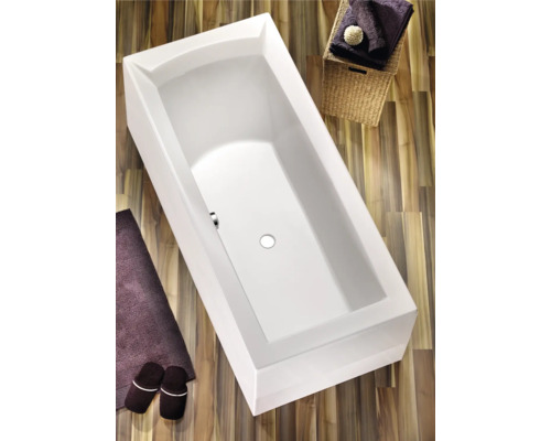 Baignoire rectangulaire avec tapis de bain et accessoires sur plancher en bois
