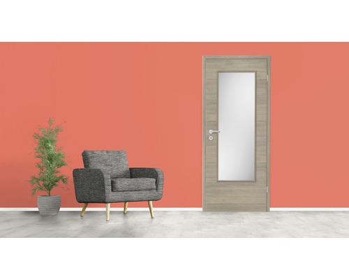 Salon avec fauteuil gris, plante d''intérieur et porte intérieure avec insert en verre.