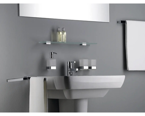 Lavabo de salle de bain avec robinet, distributeur de savon, gobelet à brosse à dents, étagère en verre et porte-serviettes dans une salle de bain lumineuse