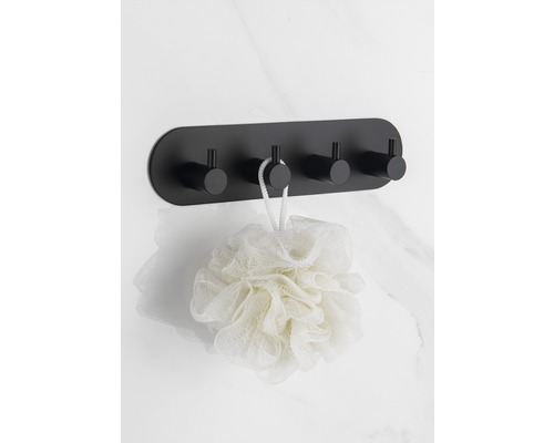 Porte-manteau mural noir avec quatre crochets et une éponge de bain sur un mur de marbre