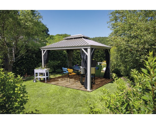 Pavillon de jardin avec table et chaises dans un jardin verdoyant.