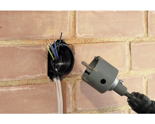 Installation d''une boîte d''encastrement dans un mur en briques avec une scie trépan