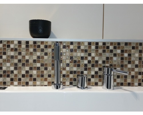 Robinet de baignoire avec douchette devant un carrelage mosaïque