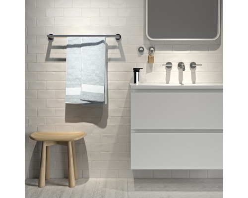 Badezimmeransicht mit Waschtisch, Spiegel, Handtuchhalter mit Handtuch und Hocker