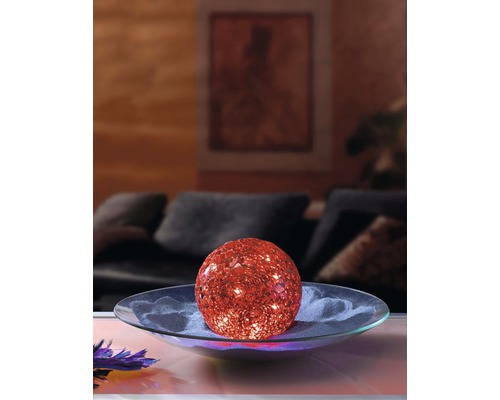 Dekorative beleuchtete Kugel auf einer Glasplatte im Wohnzimmer.