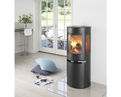 Brennender Kaminofen im Wohnzimmer mit Glasbodenplatte und Dekoration