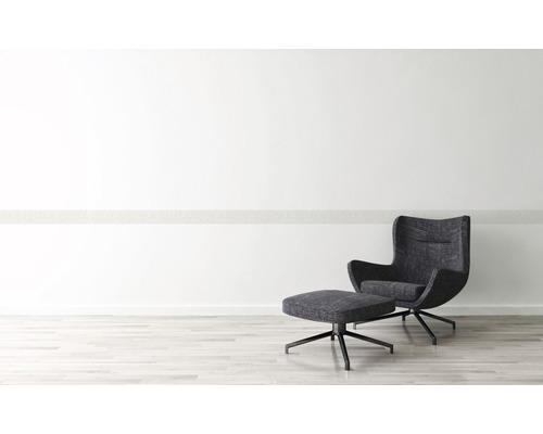 Intérieur moderne avec fauteuil et repose-pieds sur un plancher en bois clair devant un mur blanc