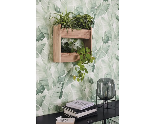 Étagère murale en bois avec plantes devant un papier peint à motif de feuilles