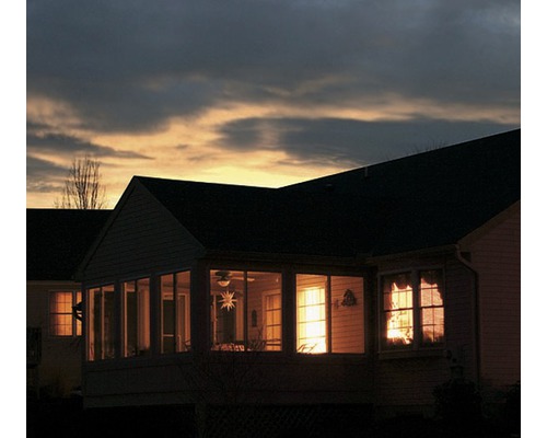Abendliche Hausansicht mit beleuchteten Fenstern und Terrasse