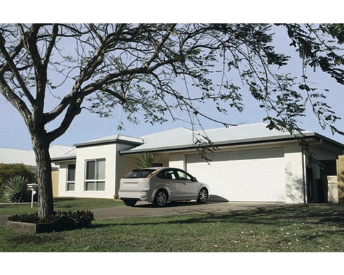 Einfamilienhaus mit Garage und Auto vor einem Baum