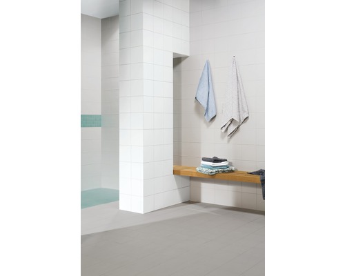 Salle de bain moderne avec carrelage blanc, banc en bois et serviettes