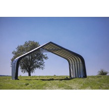 Stahlblechhalle auf einer Wiese mit Baum im Hintergrund.