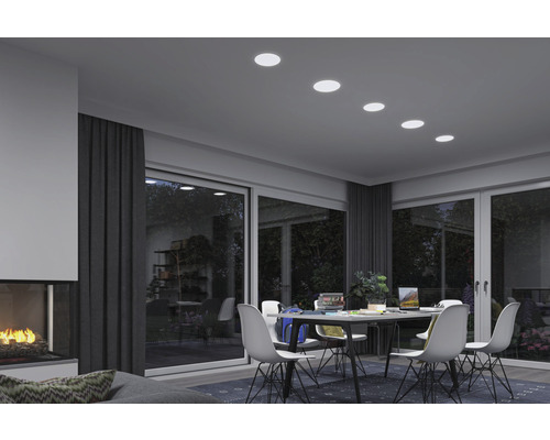 Salon avec table à manger, chaises et spots encastrés au plafond pour une ambiance lumineuse.