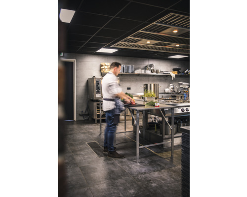 Cuisine professionnelle avec un cuisinier préparant des aliments sur des tables en acier inoxydable