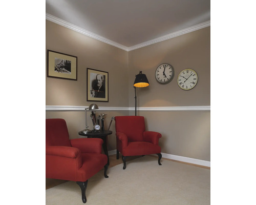 Salon aménagé de façon classique avec deux fauteuils rouges, des tableaux et des horloges au mur