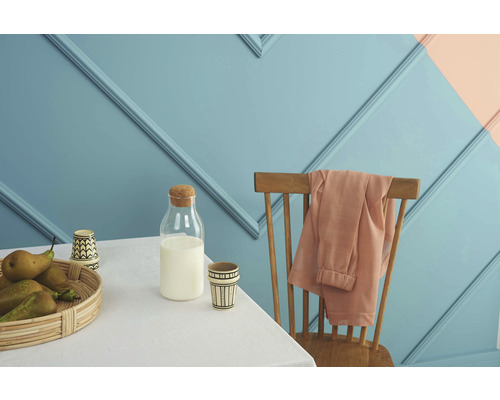 Scène avec table, chaise, bouteille de lait et corbeille de fruits devant un mur avec des moulures