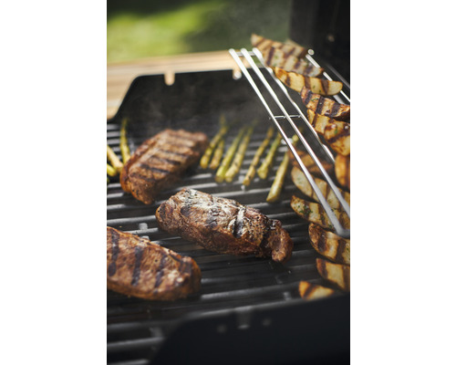Steaks, Kartoffelspalten und Spargel auf einem Grill