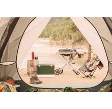Campingplatz mit Grill, Kühlbox, Thermoskanne und Stiefeln, gesehen aus einem Zelt