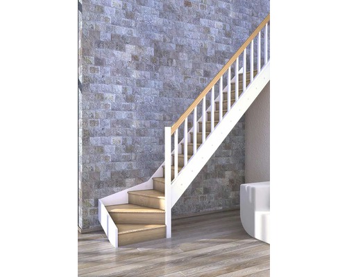 Escalier avec marches en bois et rampe blanche devant un mur de pierre