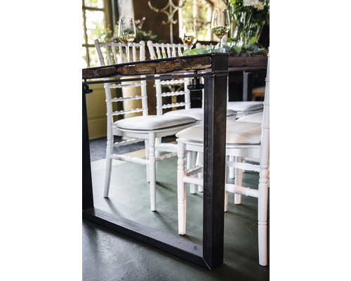 Gros plan d''une table à manger avec un cadre en métal et un plateau en bois, entourée de chaises blanches.