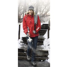 Frau mit Eisfräse auf einer verschneiten Treppe