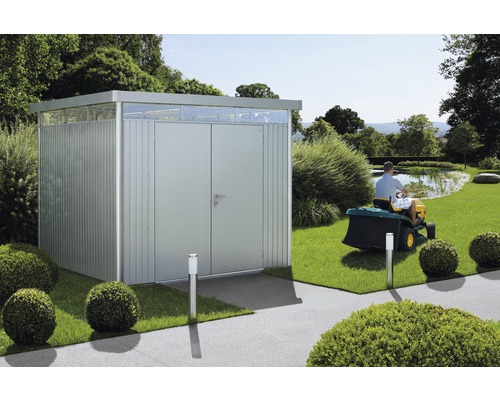 Metall-Gartenschuppen mit Doppeltür und Oberlicht in einem Garten mit Rasentraktor