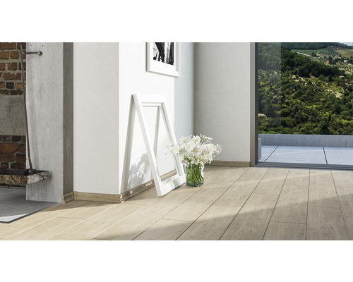 Heller Raum mit Laminatboden in Holzoptik, Fussleisten, Bilderrahmen und Blumen