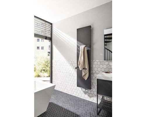 Salle de bain moderne avec sèche-serviettes, lavabo et carreaux hexagonaux.