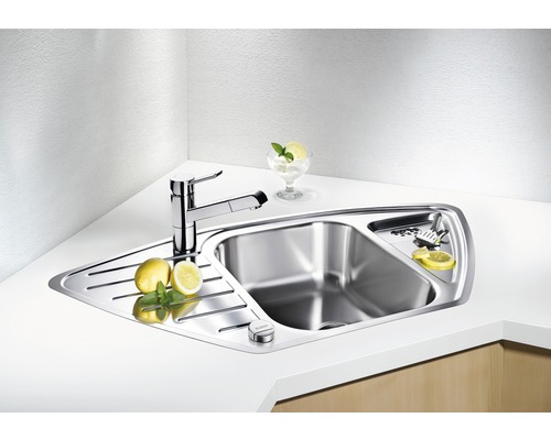 Évier d''angle en acier inoxydable avec robinet et égouttoir sur un comptoir de cuisine.