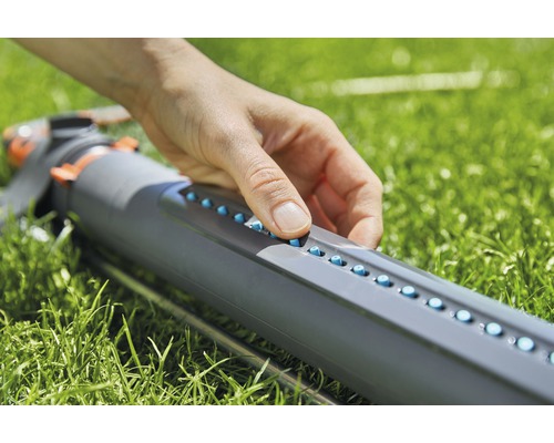 Eine Person stellt die Düsen eines Regners ein.