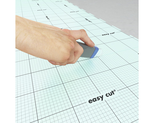 Une main coupe un tapis de découpe quadrillé avec un couteau