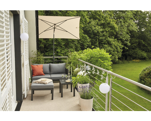 Ensemble de meubles de balcon avec parasol, canapé, tabouret et table sur un balcon donnant sur la verdure