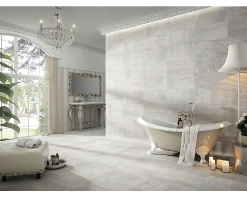 Salle de bains lumineuse avec baignoire îlot, carrelage et lustre en cristal