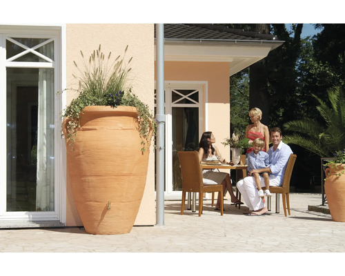 Vue du jardin avec une grande amphore servant de collecteur d''eau de pluie planté à côté d''une terrasse avec une famille