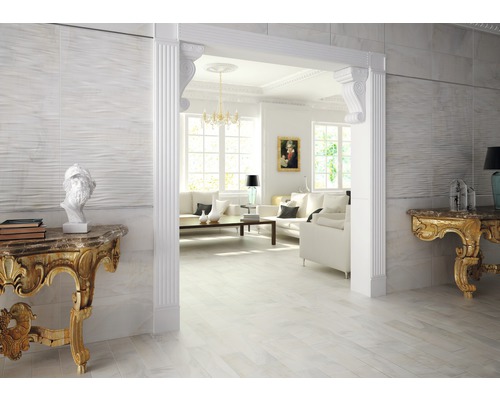 Helles Wohnzimmer mit weißen Fliesen, Stuckelementen und goldfarbenen Akzenten