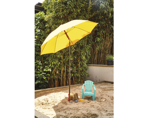 Sandkasten mit Sonnenschirm, Kinderspielzeug und Kinderstuhl im Garten.