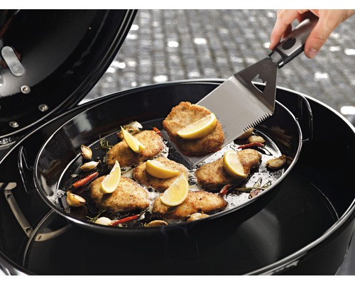 Grill mit Grillgut, Knoblauch, Chili und Zitronenscheiben, gewendet mit einem Grillwender