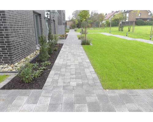Chemin pavé traversant un jardin avec des pelouses