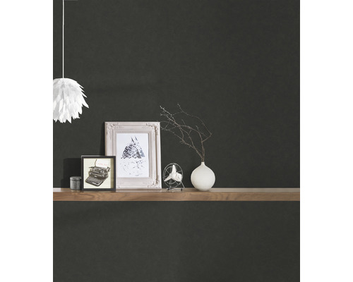 Dekoratives Regal mit Bildern, Vase und Lampe vor einer dunklen Wand