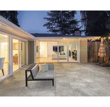 Terrasse avec sol carrelé, mobilier de terrasse et éclairage extérieur de nuit.