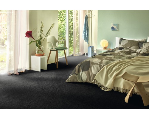 Schlafzimmer mit dunklem Teppichboden, Bett und Fenster