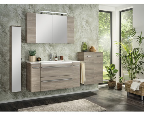 Salle de bains moderne avec lavabo, armoire de toilette et armoire haute aspect bois devant un mur à motifs végétaux.