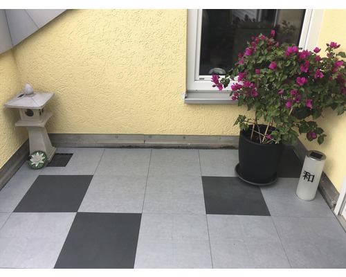 Terrasse mit Bodenfliesen, einer Steinlaterne, einer Bougainvillea im Topf und einer Solarlampe