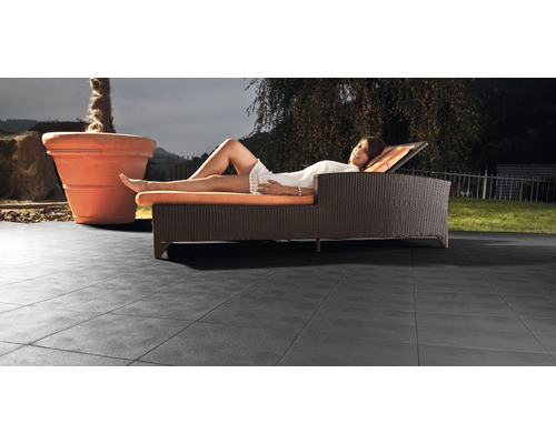 Terrasse mit Platten, Liege und Pflanzgefäss im Garten