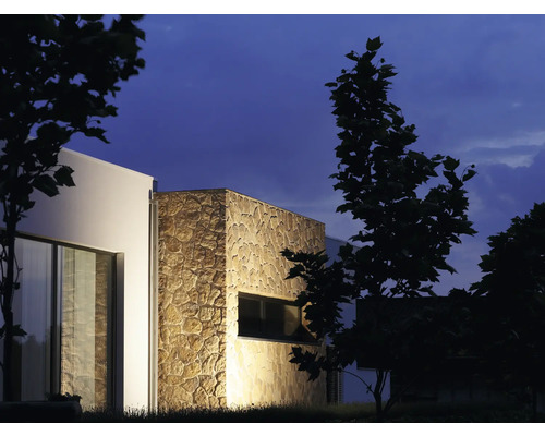 Extérieur d''une maison moderne avec parement en pierre et fenêtres la nuit