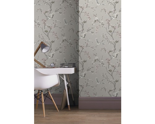 Raum mit gemusterter Tapete mit Kranichen und Blüten, Schreibtisch und Stuhl.