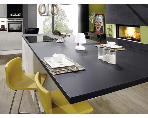 Cuisine claire avec îlot de cuisson, table à manger, chaises, vaisselle et cheminée