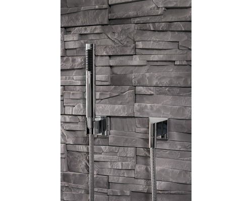 Douchette avec flexible de douche devant un mur en pierre