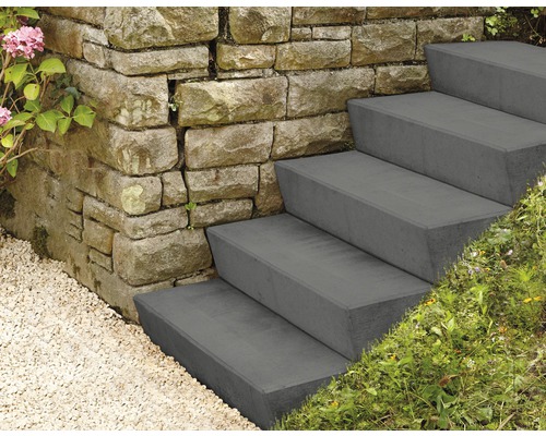 Aussentreppe aus Beton neben einer Steinmauer mit Kies und Pflanzen.