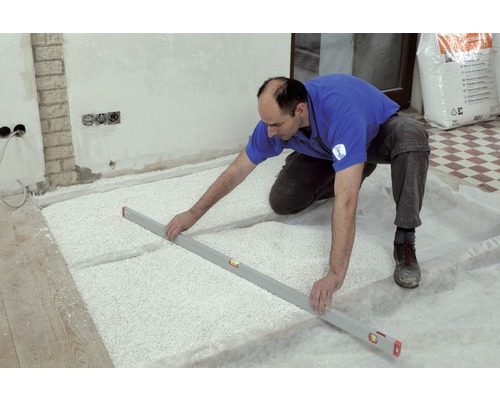 Un artisan étale un produit d''égalisation de sol avec un niveau à bulle dans une pièce.